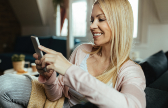 happy-woman-texting-smart-phone-while-relaxing-living-room